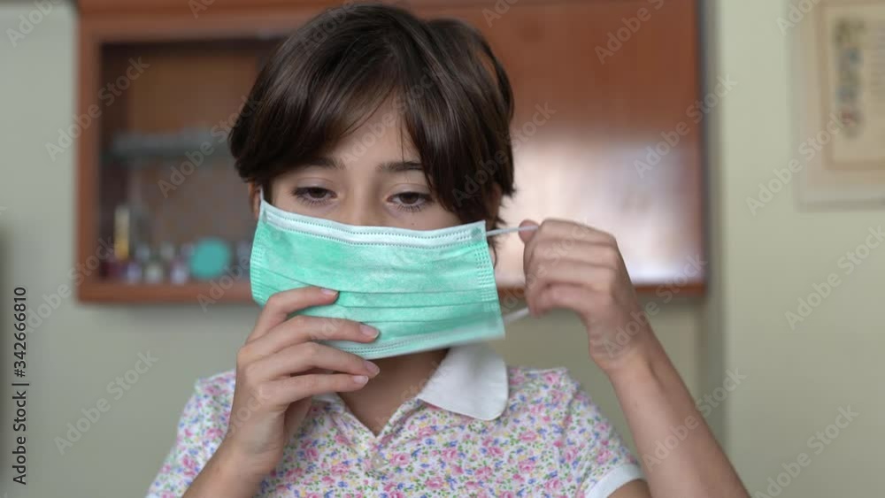 Girl putting on a medical mask at home as protection against the coronavirus. Girl putting on a medical mask at home as protection against the coronavirus.