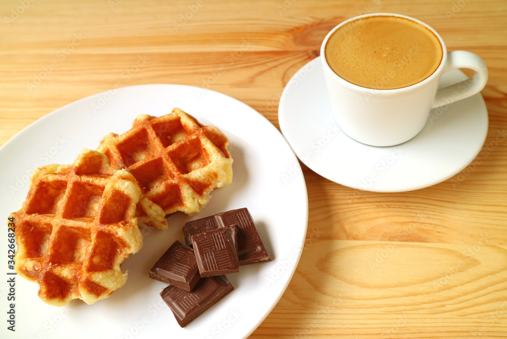 Plate of Belgian Waffles and Dark Chocolate Cubes with Espresso Coffee in the Backdrop Plate of Belgian Waffles and Dark Chocolate Cubes with Espresso Coffee in the Backdrop