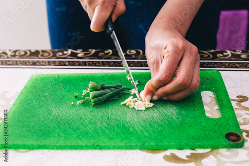 Cuts onions on a green board
