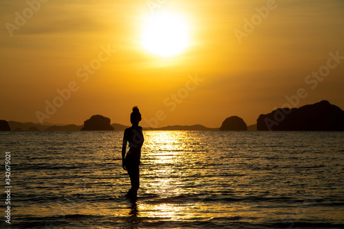 Silhouette of a girl on the beach, against the backdrop of the sea and sunset