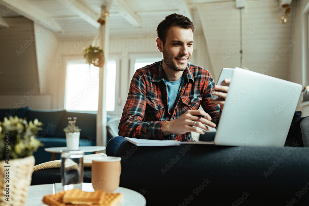 © Drazen - Happy man texting on cell phone while working on laptop at home. © Drazen - Happy man texting on cell phone while working on laptop at home.