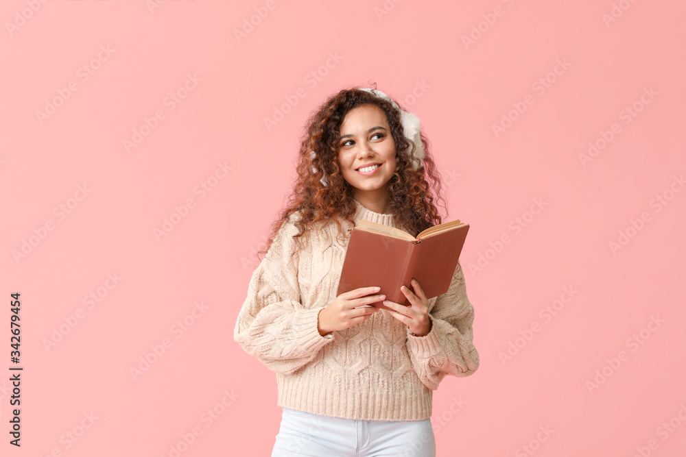 Young woman in warm sweater and with book on color background Young woman in warm sweater and with book on color background