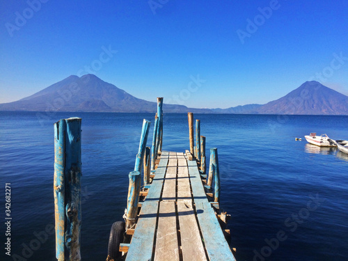 Embarcadero en Panajachel sobre el agua del Lago Atitl  n  al fondo los volcanes San Pedro  Atitl  n y Tolim  n a primera hora de la ma  ana