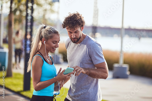 Modern couple making pause on the sidewalk during jogging / exercise.