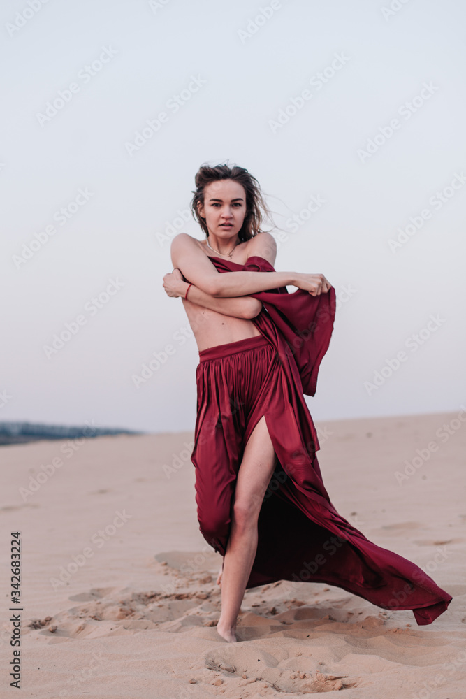 Girl with fabric stands in the wind in the desert Girl with fabric stands in the wind in the desert