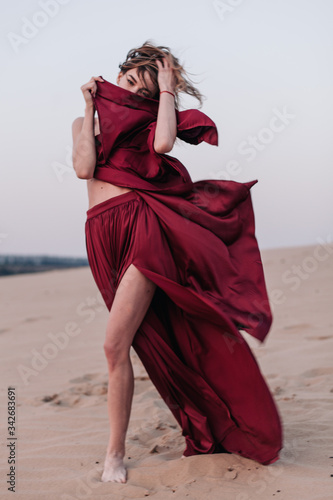 Girl with fabric stands in the wind in the desert