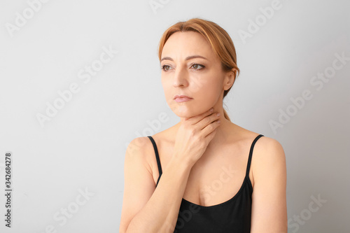 Woman with thyroid gland problem on grey background