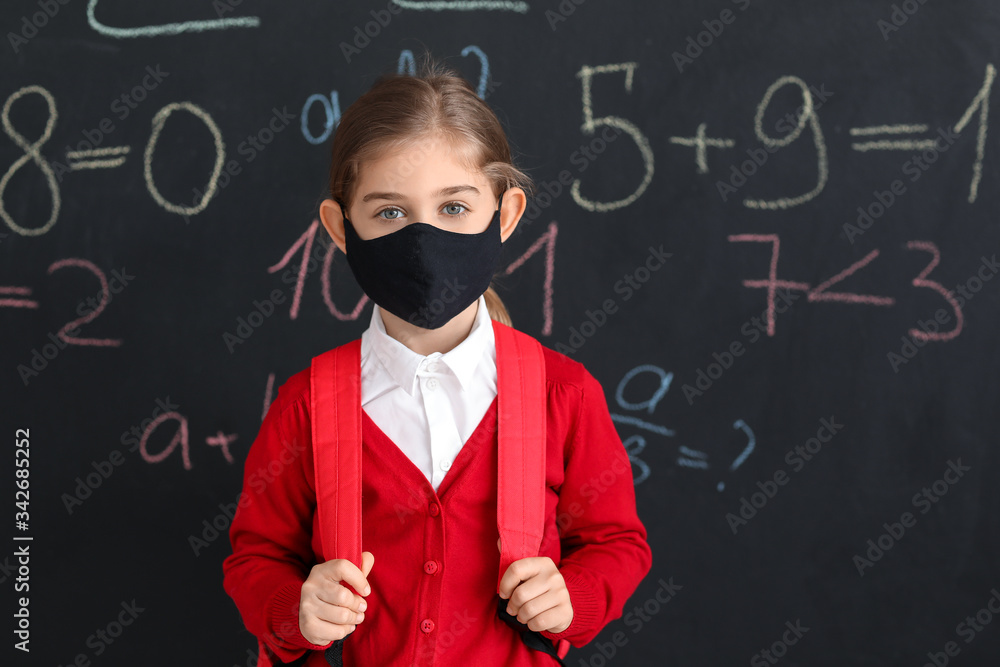 Little girl wearing medical mask near school blackboard Little girl wearing medical mask near school blackboard