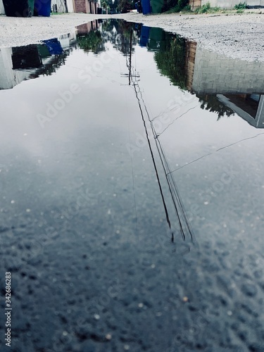 Telephone pole reflection over water in alleyway  
