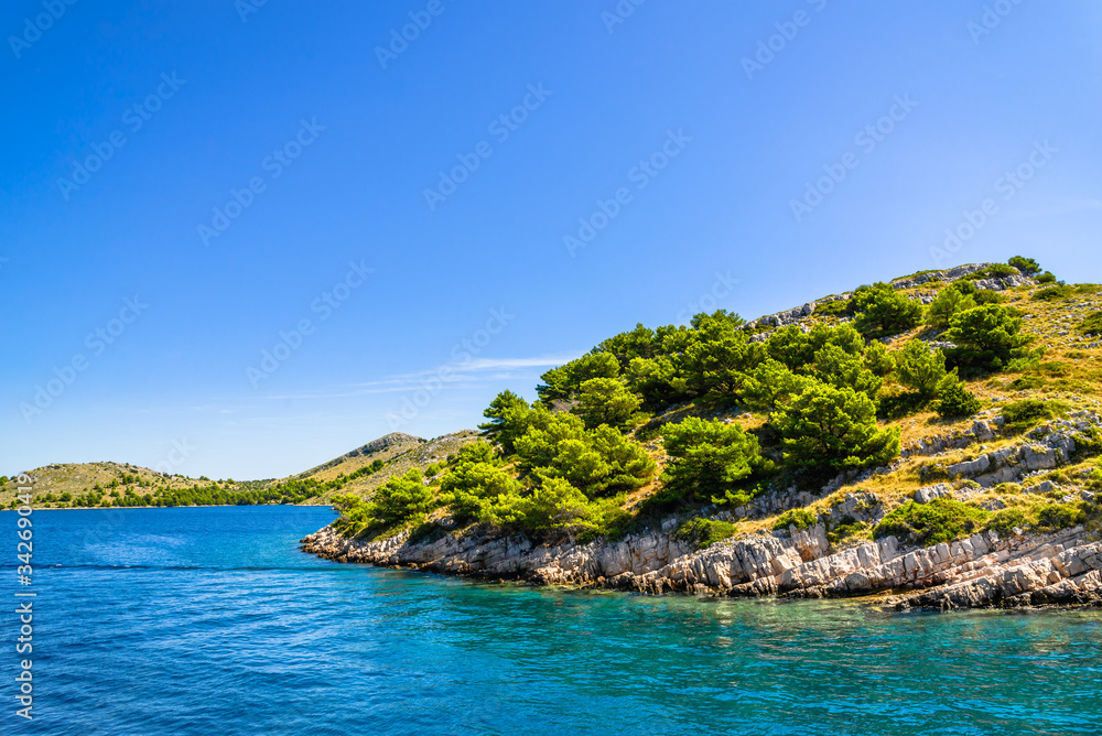 Croatian island with green pines and rocky coast. Mediterranean nature, blue sky and Sea in Croatia, vacation travel concept.