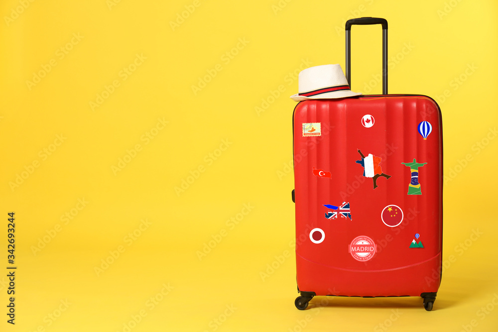 Red suitcase with travel stickers on yellow background. Space for text Red suitcase with travel stickers on yellow background. Space for text