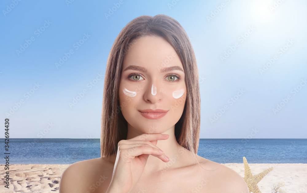 Young woman with sun protection cream at beach