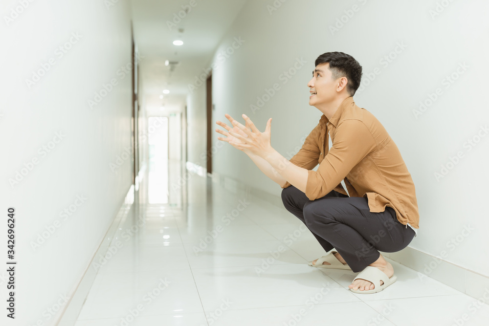 Depressed and sad woman sitting on the floor in a corridor. Low key.