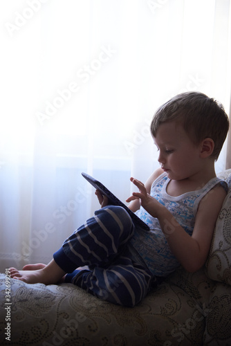 A little boy plays with a tablet at home