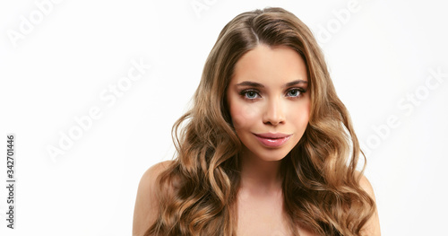 Portrait of young beautiful woman isolated at white background. Blonde girl with long and shiny wavy hair . Smiling friendly girl with curly hairstyle