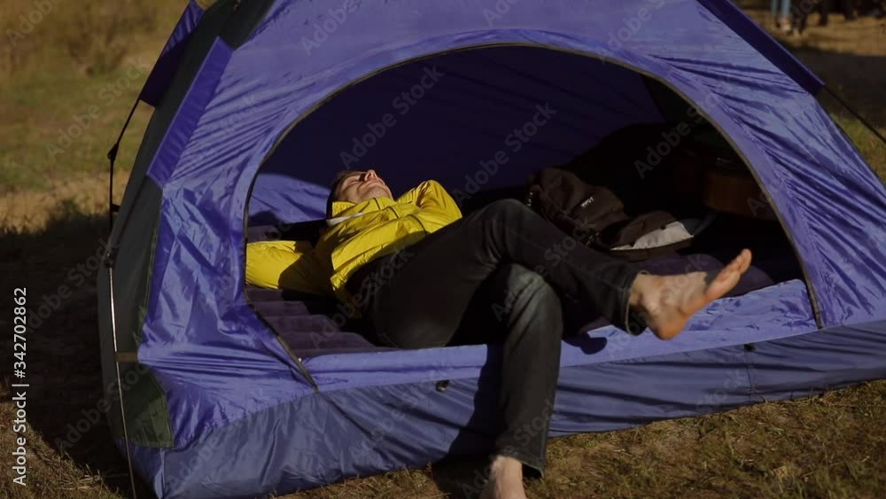 Man with barefoot legs relaxing in a camp tent Man with barefoot legs relaxing in a camp tent