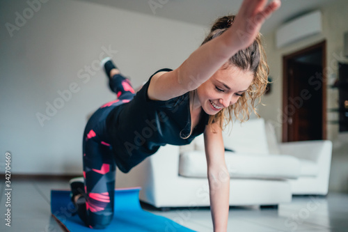 giovane bella ragazza fa sport a casa eseguendo esercizi a corpo libero. Smart gym e distanza sociale durante la pandemia 