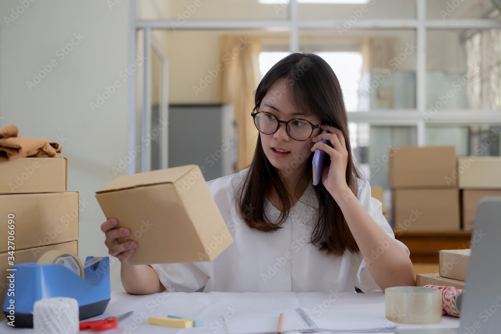 Young online seller talking on phone to receive and checking order from customers Young online seller talking on phone to receive and checking order from customers