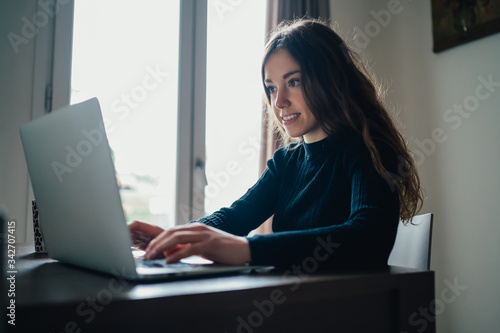 Giovane bella ragazza studente/ lavoratrice studia/ lavora da casa con il computer. Smart working e distanza sociale. Lavorare con la tecnologia 