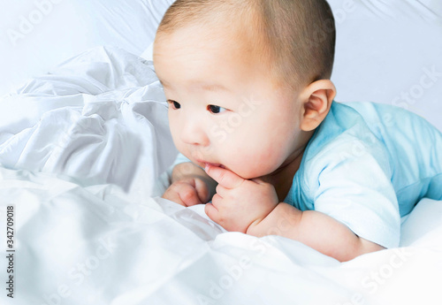 Portrait of a newborn Asian cute baby boy wore blue Infant bodysuit crawling on the bed , Charming Fat baby 5 month old enjoy and happy,soft selective focus