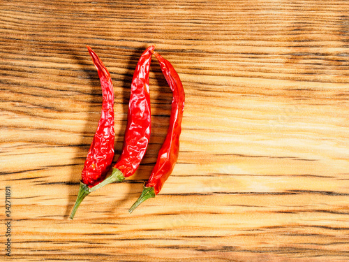 Three pods spice red chili pepper on wood background with copy space