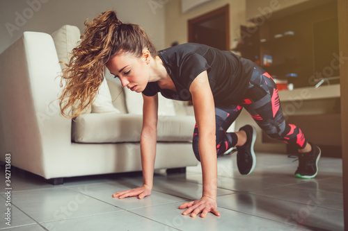 Giovane bella ragazza realizza esercizi fisici a casa. Esercizi funzionali a corpo libero nel salotto di casa  photo