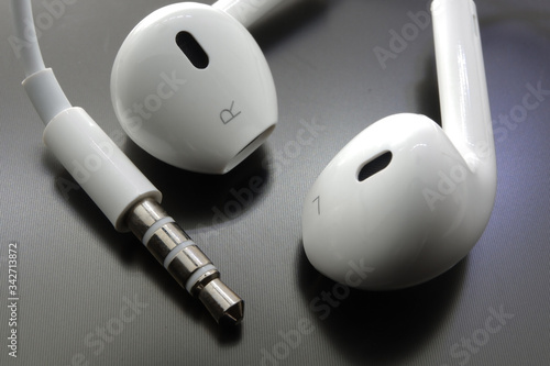 White earphone earbud type and its audio jack with black reflective background
