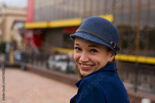 Stylish young lady on the street walks in spring in blue coat and cap.