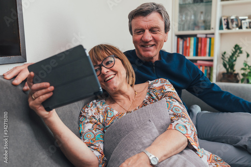 Coppia di europei di mezza età realizza una video chiamata con la famiglia. Tablet, laptop, smartphone. Distanza sociale e tecnologia  photo