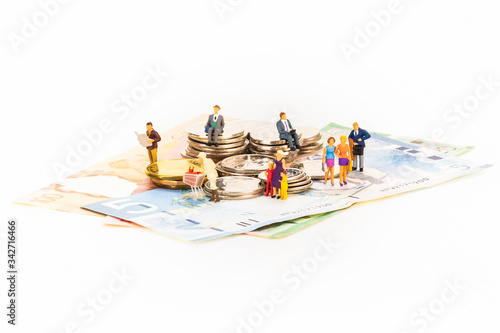 Canadian dollars and coins with miniature people on white background