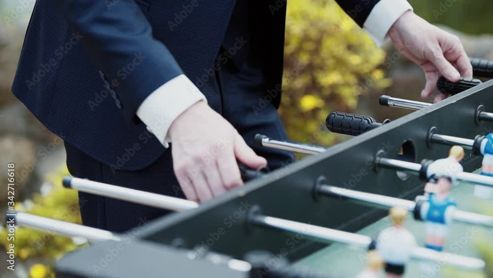 Caucasian man hands in suit plays kicker, table football, actively twists grips Caucasian man hands in suit plays kicker, table football, actively twists grips