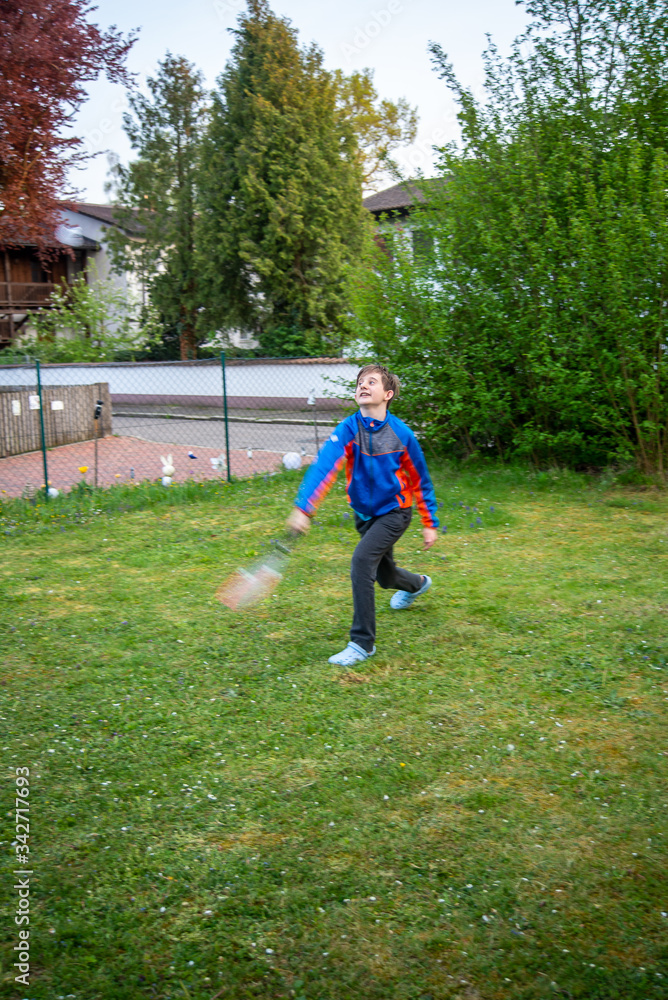Boy plays badminton in his backyard during the coronavirus lockdown measures