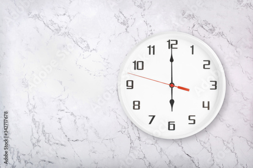 White round wall clock on white natural marble background. Six o'clock, 6 a.m. or 6 p.m.