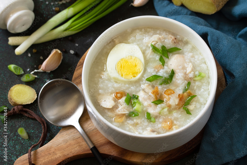 Arroz Caldo Soup. Hot soup with ginger chicken rice and garlic in a bowl on a dark countertop. Arroz Caldo Soup. Hot soup with ginger chicken rice and garlic in a bowl on a dark countertop.