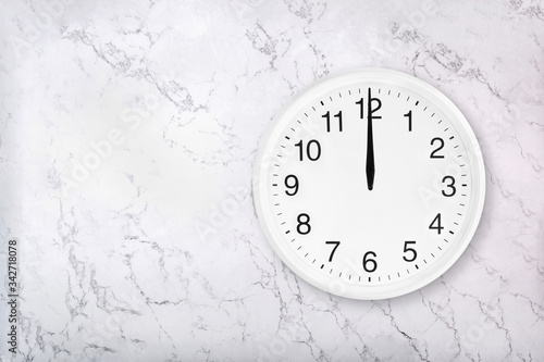 White round wall clock on white natural marble background. Twelve o'clock. Midday or midnight. 12 a.m. or 12 p.m