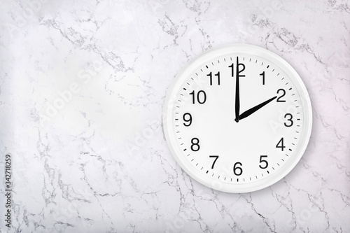 White round wall clock on white natural marble background. Two o'clock. 2 a.m. or 2 p.m