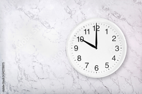 White round wall clock on white natural marble background. Ten o'clock. 10 a.m. or 10 p.m