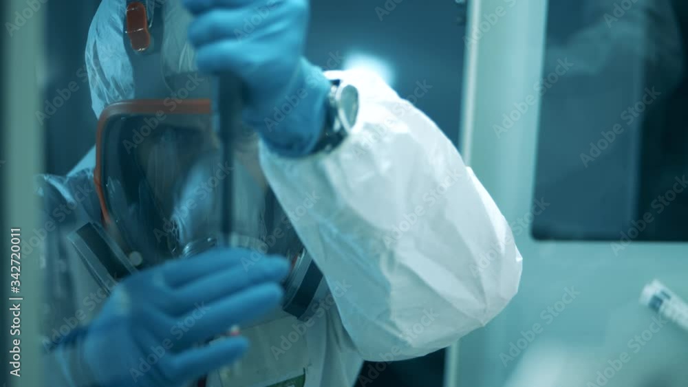 Lab worker in a protection suit is doing a chemical research. Covid-19, coronavirus concept. Lab worker in a protection suit is doing a chemical research. Covid-19, coronavirus concept.