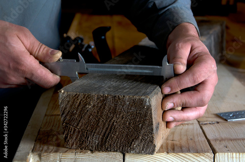 carpenter measures with a caliper a wooden beam