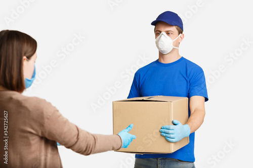 Client in protective mask, takes box from courier © Prostock-studio