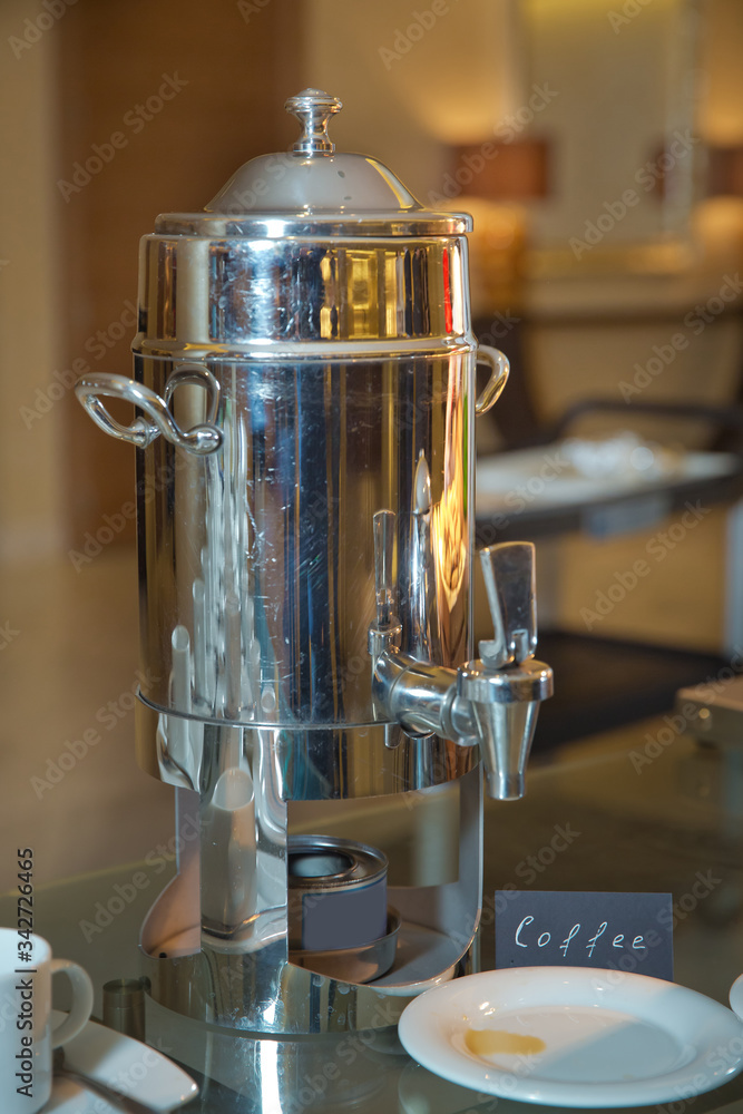 Hot beverages catering. Metal milk cap for coffee . Thermos with hot water  and cups for afternoon coffee on the wood table in luxury five star hotel.  Stock Photo