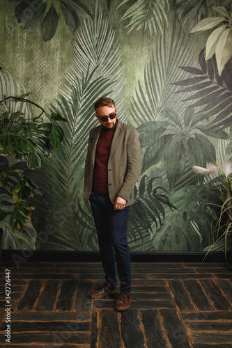 Portrait of young beautiful fashionable man against green wall. © Alexandr
