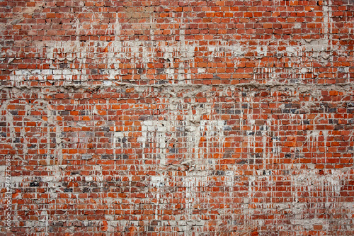Fragment of an old brickwork of an old building. Potholes and defects of red brick. White drips on a red brick wall.