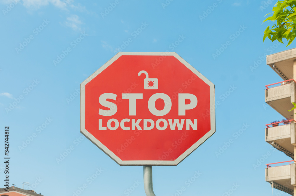 Stop lockdown concept: a stop street sign with the text stop lockdown with a blue sky on the background and some houses and trees around Stop lockdown concept: a stop street sign with the text stop lockdown with a blue sky on the background and some houses and trees around
