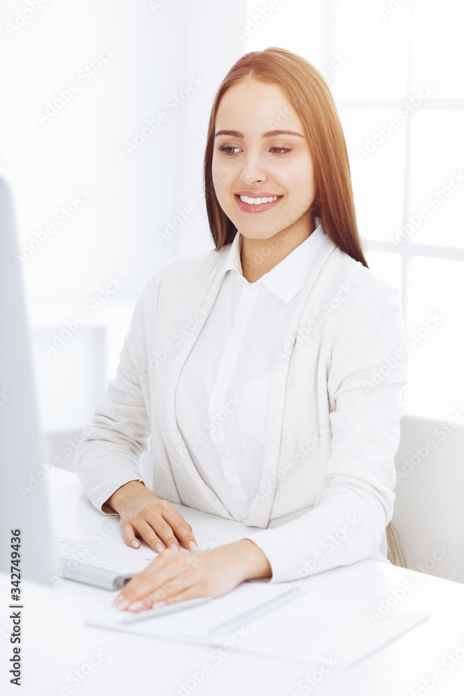 Business woman sitting and working with computer in white office. Student girl studying or secretary making report. Success concept Business woman sitting and working with computer in white office. Student girl studying or secretary making report. Success concept