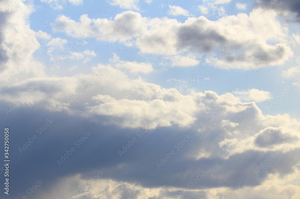 Fototapeta premium Clouds in the blue sky at sunset or dawn backlit by the sun. Place for text and design.