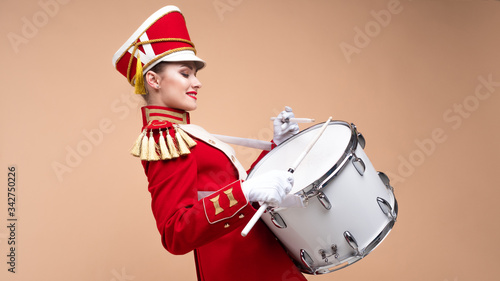 Bild auf Leinwand Charming cheerful drummer in a red uniform, sings and plays the drum