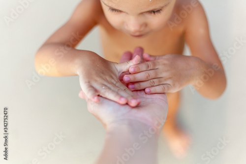 A small child on the beach plays with his mother's hand. A story of trust and love.