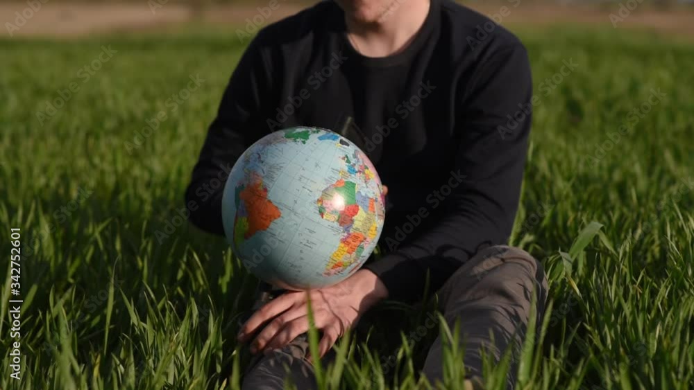 man spinning earth globe sitting in green field
man spinning earth globe sitting in green field