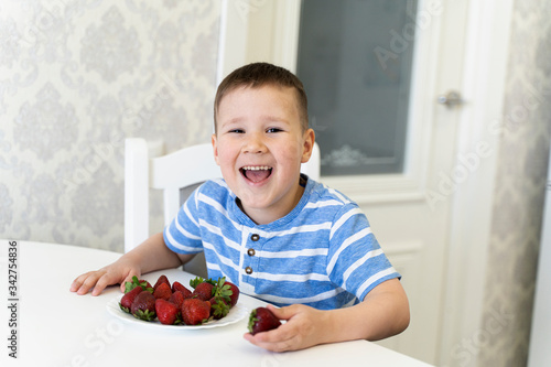 funny child laughs and eats strawberries. spring. April-may.
